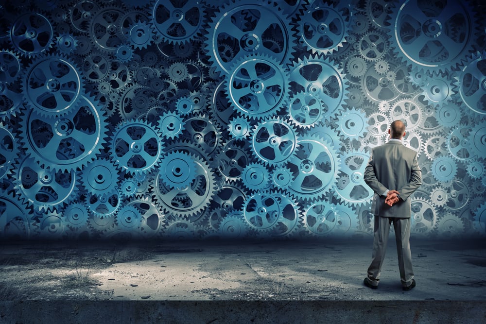 photo of businessman looking at cogwheels